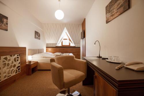 a bedroom with a bed and a desk with a chair at Hotel Termál in Vyhne