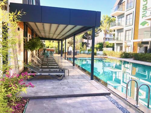a swimming pool with lounge chairs next to a building at Juglans Suites in Fethiye