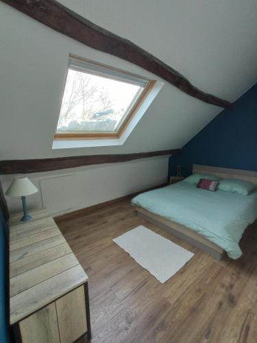 une chambre mansardée avec un lit et une fenêtre dans l'établissement Le refuge, à Biollet