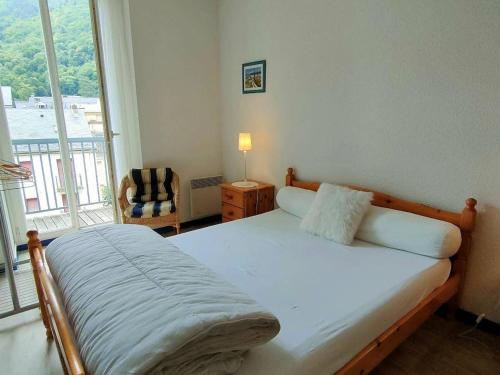 a bedroom with a bed and a chair and a window at Appartement Cauterets, 2 pièces, 4 personnes - FR-1-234-93 in Cauterets