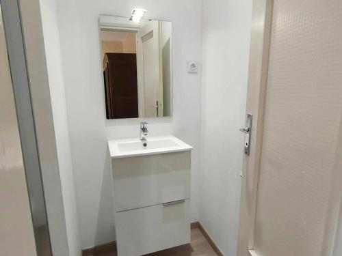 une salle de bain blanche avec un lavabo et un miroir dans l'établissement Appartement cosy avec balcon, proche thermes et télécabine, Cauterets - FR-1-234-135, à Cauterets