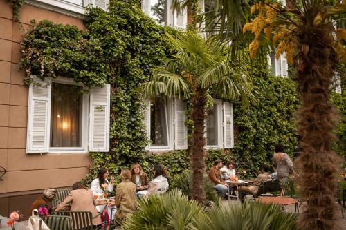 a group of people sitting at tables outside a building at Parkhotel Mondschein, a Member of Design Hotels in Bolzano