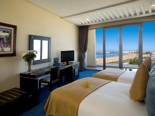 een hotelkamer met 2 bedden en een bureau met een computer bij Atlas Essaouira Riad Resort in Essaouira