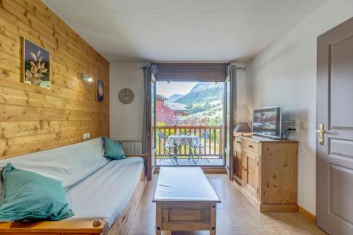 1 Schlafzimmer mit einem Bett und einem Balkon mit einem Tisch in der Unterkunft Les Chevreuils des Evettes in Flumet