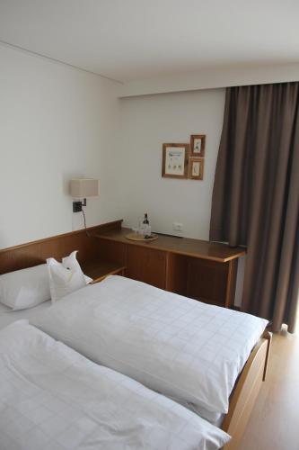 a bedroom with a white bed and a desk at Garni Hotel Max in Santa Cristina in Val Gardena