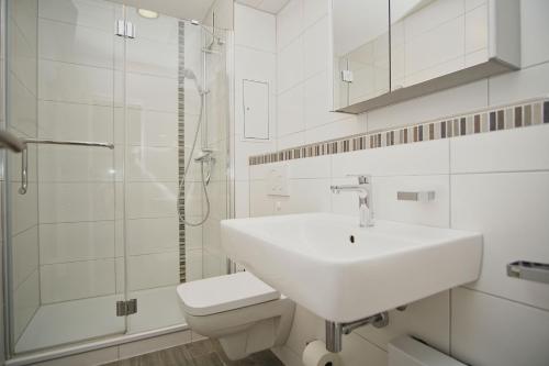 a white bathroom with a sink and a toilet at gemütliche Ferienwohnung in Hafennähe - FeWos am Hochzeitsberg FeWo 10 in Breege