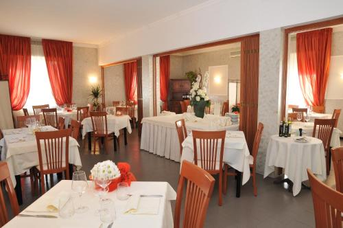 a restaurant with white tables and chairs with flowers on them at Hotel Mini Palace - Country House in Molinella