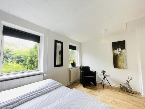 a bedroom with a bed and a chair and a window at aday - Quiet and cozy house in Aalborg