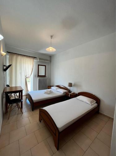 una camera da letto con due letti e una scrivania di Balogiannis Hotel a Paralia Pantaleimonos