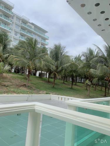 a swimming pool with palm trees and a building at Comfortable Family Apartment at Sealinks Mui Ne in Ấp Ngọc Hải