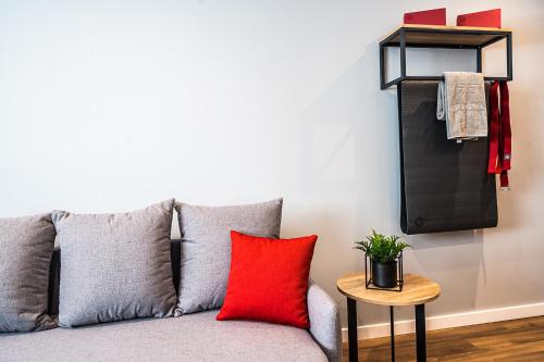 a couch with a red pillow and a side table at Up Hotel Budapest in Budapest