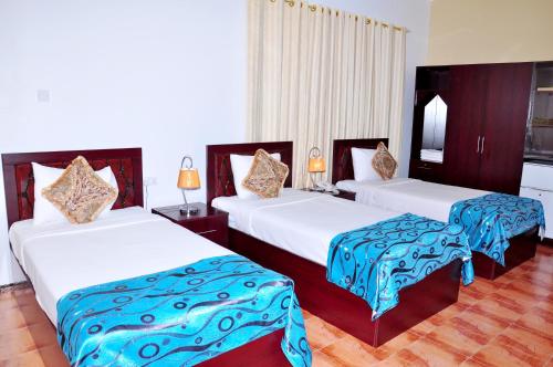 a bedroom with two beds with blue and white sheets at Majan Guest House L.L.C. in Nizwa