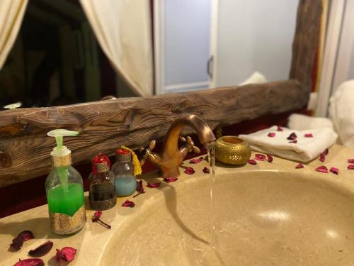 a bathroom sink with spilled cosmetics and a mirror at Desert Heart Luxury Camp in Merzouga