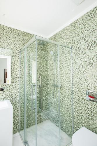 a glass shower in a bathroom with a tile wall at Sra da Oliveira Solar Heritage in Leiria