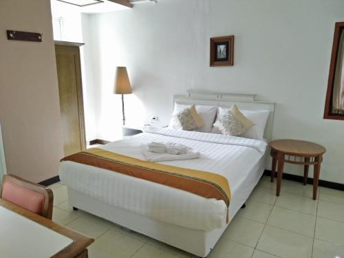 a bedroom with a large white bed and a table at JL Bangkok Hotel in Bangkok