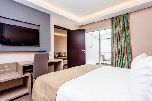 a hotel room with a bed and a desk and a television at Amadil Ocean Club in Agadir