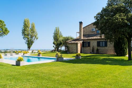 an estate with a swimming pool in front of a house at Serra Country House in Gradara