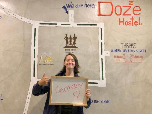 a woman holding up a sign that says gordonory sidx at Doze Hostel in Chiang Mai