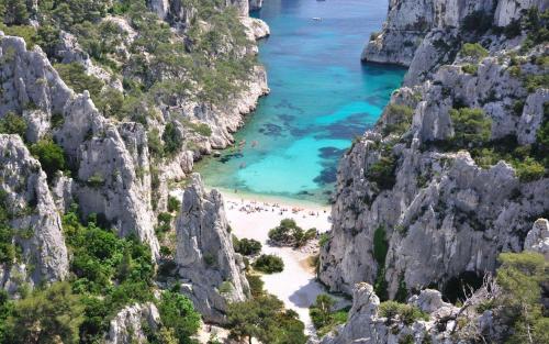 a view of a beach between two rocky cliffs at HôTEL LES VOLETS ROUGES - CASSIS in Cassis