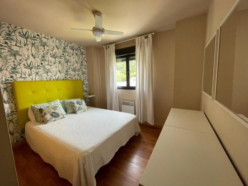 1 dormitorio con 1 cama con cabecero amarillo y ventana en Apartamento Unquera - Val de San Vicente en Unquera