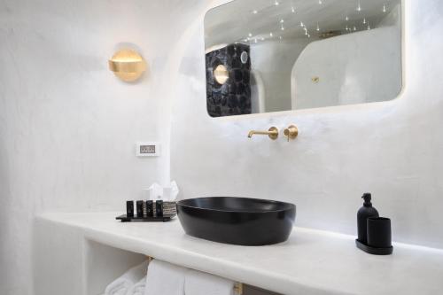 a bathroom with a black sink and a mirror at Alme Luxury Cave Villas in Vóthon