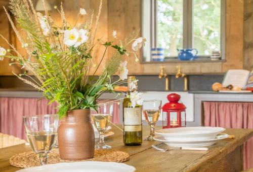 una mesa con platos y vasos y un jarrón con flores en Snow Hall Barn, en Peasenhall