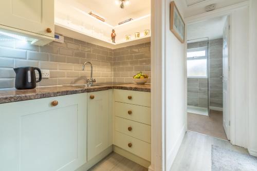 a kitchen with white cabinets and a sink at Hideaway Cottage in Leiston