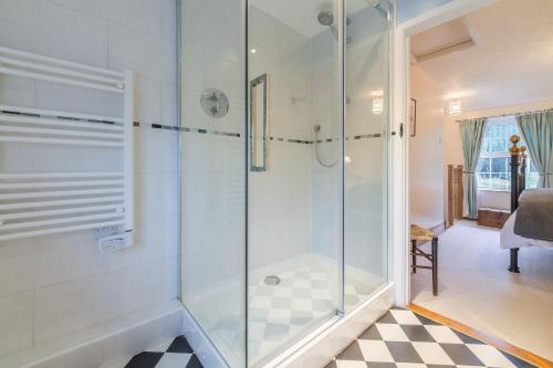 a shower with a glass door in a bathroom at Flint Cottage in Wenhaston