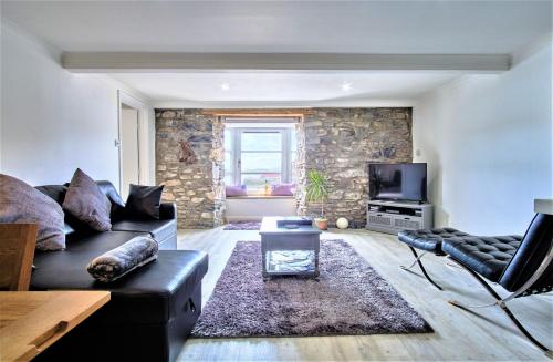 a living room with a black couch and a tv at Imperial Apartment in Oban