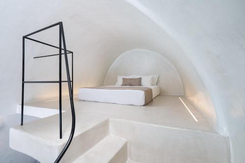 a white room with a bed and a staircase at Alme Luxury Cave Villas in Vóthon