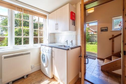 a kitchen with a sink and a washer and dryer at Honeypot Cottage in Ipswich
