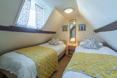 1 dormitorio en el ático con 2 camas y ventana en Bovis Cottage en Southwold