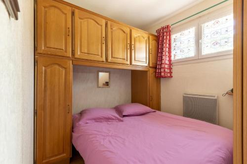 - une chambre avec un lit rose et des placards en bois dans l'établissement Le Montagnard, à La Bresse