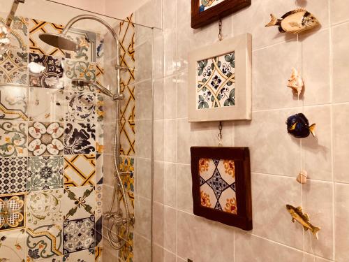 a bathroom with a shower and mosaics on the wall at The Flowers' House in Potenza
