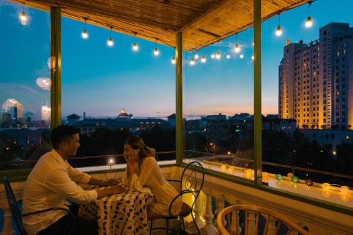 a man and a woman sitting on a balcony at night at Eden Westlake Hotel in Hanoi