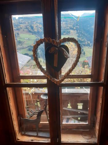 a heart hanging on a window with a view at Hüttenzauber in Taxenbach