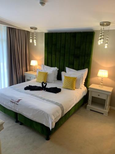 a bedroom with a large bed with a green headboard at HOTEL CARPAT INN in Azuga