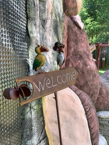 two birds sitting on a welcome sign on a tree at HOTEL CARPAT INN in Azuga