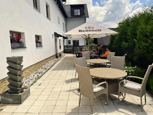 a patio with tables and chairs and an umbrella at Penzion Alfa in Železná Ruda