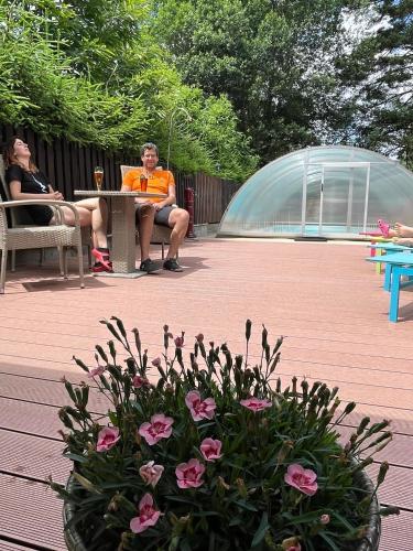 a man in an orange shirt sitting at a table in a garden at Penzion Alfa in Železná Ruda