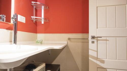a bathroom with a sink and a red wall at Capricho Toledano in Toledo