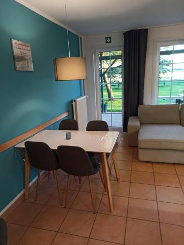a dining room with a table and chairs and a couch at Tjarkshof in Friedrichskoog
