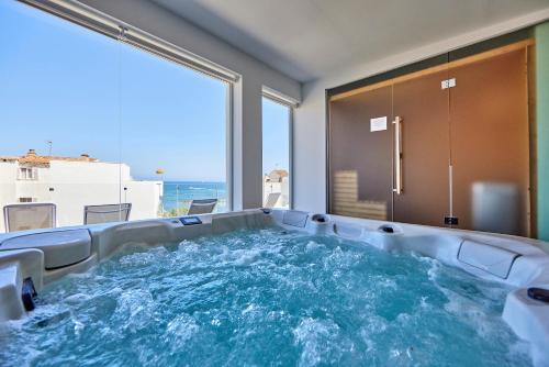 a hot tub in a room with a view of the ocean at Hotel Ilusion Moreyo - Adults Only in Cala Bona