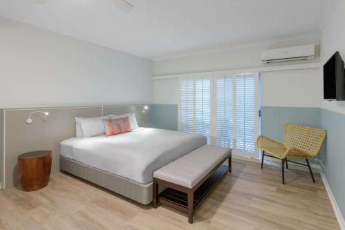 a bedroom with a bed, chair, desk and a lamp at Ramada Resort by Wyndham Port Douglas in Port Douglas