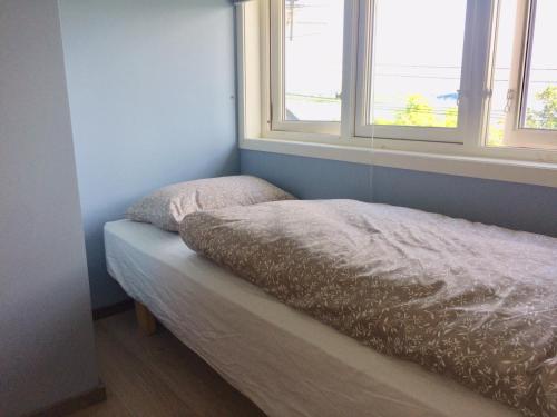 a bed sitting in a room with two windows at tau bed and breakfast in Strand