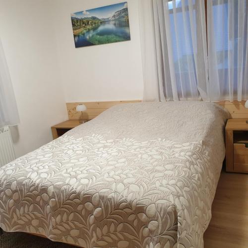 a white bed in a bedroom with a window at Apartmaji Pri Medvedu in Bohinj