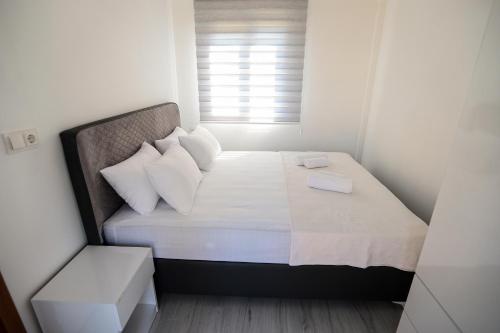 una piccola camera da letto con un letto con lenzuola e cuscini bianchi di Linaden Apart a Kumluca