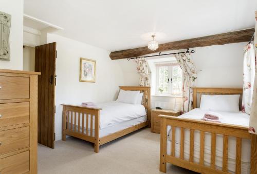 a bedroom with two beds and a window at Hope Cottage in Quenington