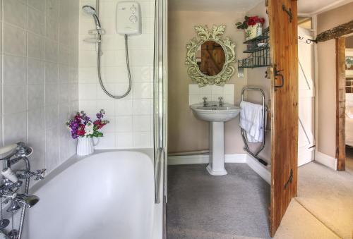y baño con bañera y lavamanos. en Bay Tree Cottage, en Shipton under Wychwood