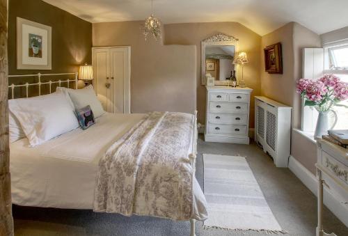 a bedroom with a bed and a dresser and a mirror at Bay Tree Cottage in Shipton under Wychwood